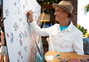 Artist wearing hat painting on a canvas